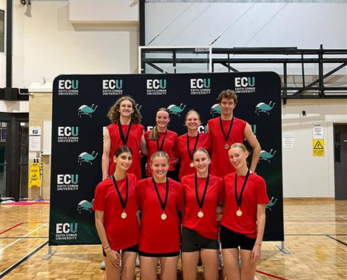 Netball players in front of an ECU banner