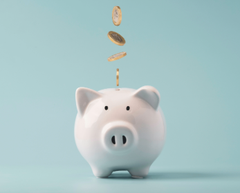 A piggy bank on a blue background with coins falling into the top.