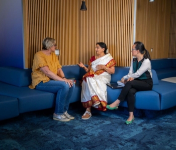 Three people sitting together chatting.