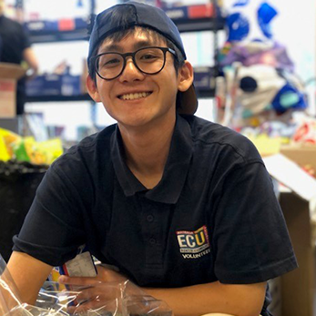 Student with cap and glasses packing Christmas hampers