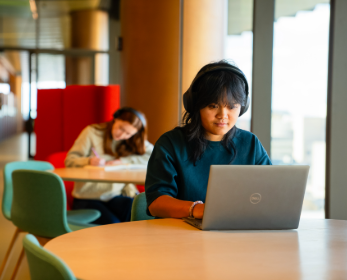 Student using a laptop while studying at a table on campus.