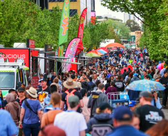 A photograph of the Telethon Family Festival on Wellington Street. there are food trucks lined up on the left side, and the road is crowded with people. You can see the edge of the ECU City Campus building in the background.